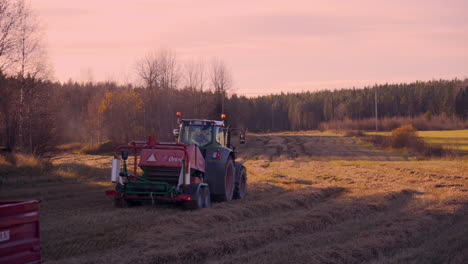 Pan-shot-of-a-tractor,-harvesting-on-a-wheat-field,-on-the-countryside,-on-a-sunny,-autumn-evening,-in-Soderhamn,-Sweden