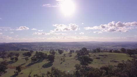 Aerial-flight-over-forest-in-Australia-with-sun-and-clouds-in-the-background,-extreme-long-distance-shot-moving-forward