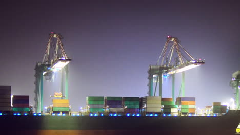 Loading-a-container-ship-at-night,-ZOOM-OUT-EASE