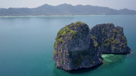 Aerial-arch-shot-of-large-rock-formation-in-blue-ocean-in-Thailand---camera-circling