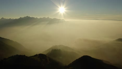 Flying-high-above-mist-layer-at-sunset-in-alpine-environment