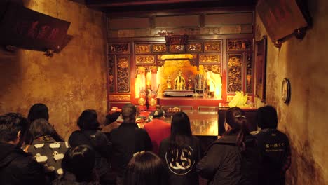 Slow-motion-shot-of-Asian-people-praying-indoors-at-Dalongdong-Baoan-Temple-in-Taipei,-Taiwan