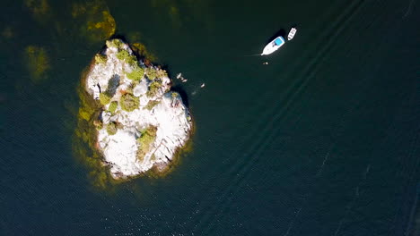 4K-Luftaufnahme-Von-Menschen,-Die-Vor-Einer-Felsigen-Insel-Schwimmen