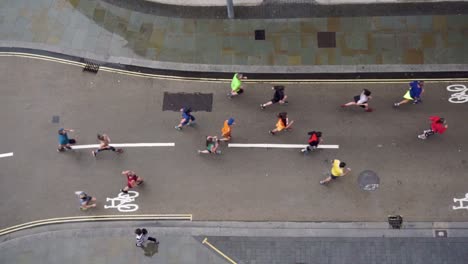 Slo-mo-direct-downwards-aerial-view-of-runners-on-street-corner