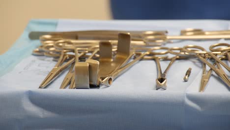 Close-up-of-a-sterile-surgical-tray-full-of-operating-instruments-with-motion-a-healthcare-worker-moving-in-the-background