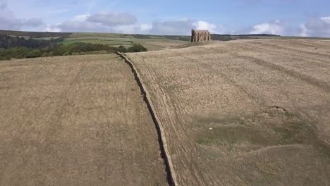 Aerial-tracking-forward-up-a-the-brow-of-a-hill-to-reveal-the-amazing-St-Catherine's-Chapel,-just-next-to-the-village-of-Abbotsbury