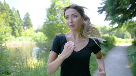 View-of-a-woman's-face-as-she-begins-jogging-in-a-wooded-area-near-a-pond