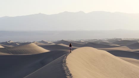 Ultra-slow-motion-shot-of-woman-balancing-on-sand-dune-in-the-desert-in-Death-Valley-National-Park-in-California,-USA
