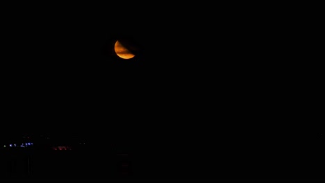 Red-half-moon-rises-over-the-lake,-timelapse