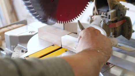 Close-up-shot-on-a-construction-worker-cutting-a-piece-of-angle-iron-on-a-metal-miter-chop-saw-in-a-workshop