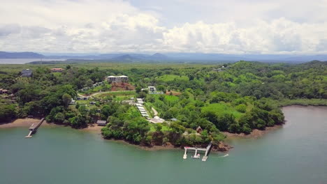 Horizontal-drone-shot-of-beautiful-vacation-location-next-to-the-sea-in-a-forest-with-mountain-and-cloudy-sky-background,-Boca,-Chica,-Panama