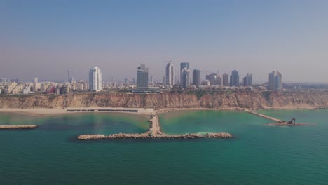 The-coastline-of-Netanya-in-Israel,-shot-from-the-sea-in-front-of-stone-pier