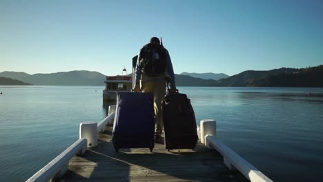 Male-passenger-with-backpack,-luggage-and-suitcase-boarding-walking-on-dock-and-boarding-boat-in-the-morning-during-sunrise