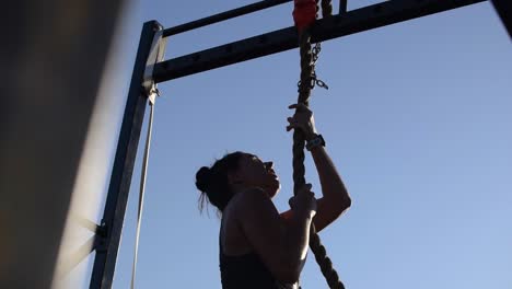 Female-Athlete-Reaching-the-Top-of-a-Rope-Climb-at-a-Cross-Fit-Competition