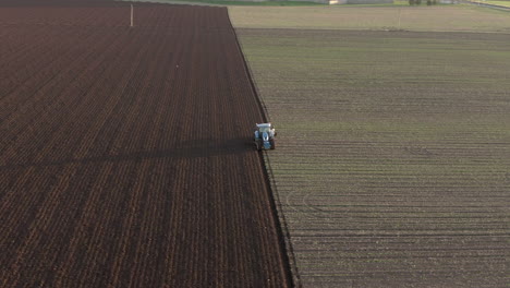 Aerial-view-of-a-farm-tractor-ploughing-a-field-in-Aberdeenshire-on-a-sunny-day,-Scotland