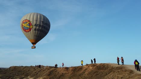 A-hot-air-balloon-flies-over-the-peak-of-Goreme-in-Cappadocia,-Turkey