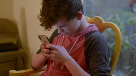 Teenage-boy-involved-in-texting-his-new-iPhone-x,-shut-out-from-his-surroundings