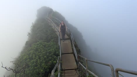 Young-woman-walks-through-cloud,-high-on-the-Haiku-Stairs