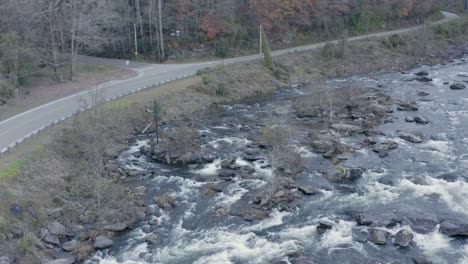 Drone-shot-of-river-and-road-low-altitude-panning-up-and-right-in-late-fall-in-western-North-Carolina