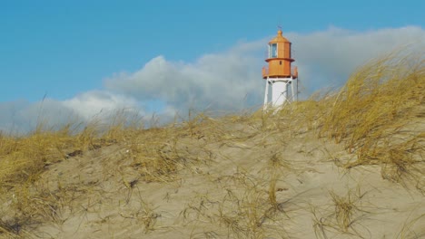View-trough-the-dunes-to-the-Pape-beach-lighthouse-in-sunny-winter-day,-wide-shot