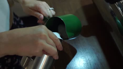 SLOWMO---Professional-female-barista-stirs-the-milk-and-pours-to-other-frothing-jug