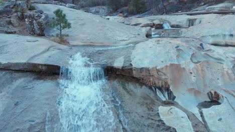 Aerial-dolly-shot-moving-right,-of-cascading-waterfalls-flowing-over-granite-rock
