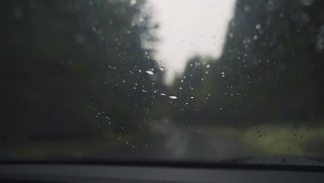 Nahaufnahme-Von-Nassem-Regen,-Der-In-Zeitlupe-Auf-Die-Windschutzscheibe-Trifft-Und-Von-Fensterwischern-Gereinigt-Wird