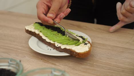 SLOWMO---Preparing-Avocado-on-toast-bread-with-black-and-white-sesame-seeds-and-hummus