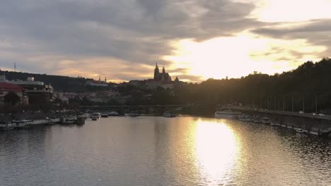 Betrachten-Sie-Die-Prager-Burg-Von-Der-Moldau-Aus,-Während-Ein-Feuriger-Sonnenuntergang-Den-Himmel-Erleuchtet