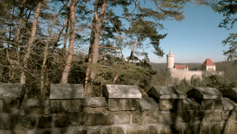 Viewing-Kokorin-Castle-in-Czech-Republic-through-the-trees-from-nearby-stone-wall-ramparts