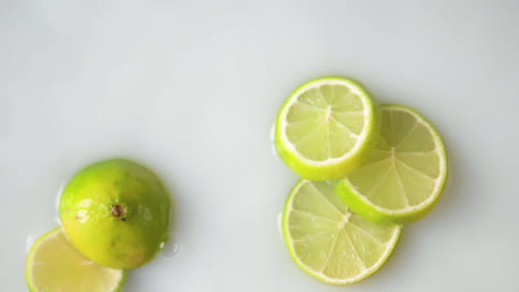 Sliced-citrus,-lime-falling-in-white-liquid