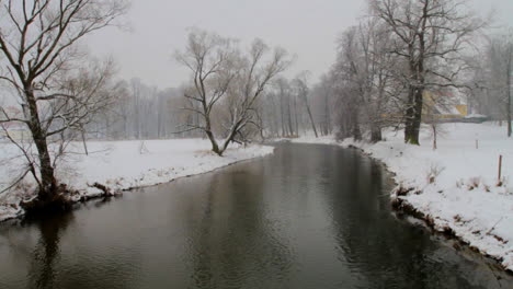 Der-Fluss-Fließt-Langsam-In-Einer-Schneebedeckten-Winterlandschaft