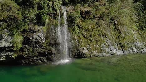 Beautiful-waterfall-on-beautiful-pristine-blue-clear-Pelorus-river,-New-Zealand-with-rocks-and-native-lush-forrest-in-background---Aerial-Drone