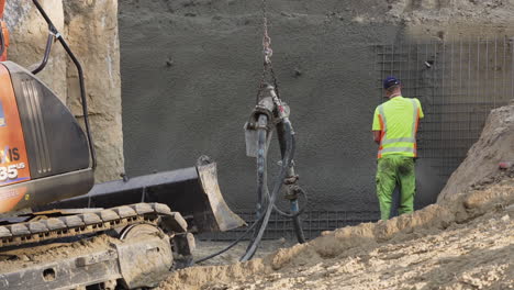 Man-spraying-cement-onto-a-steel-armature-wall-with-a-nozzle-and-a-hose-in-Vienna,-Austria