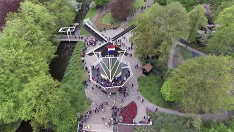 A-drone-shot-of-a-Dutch-windmill-with-people-around-it,-panning-back-and-up,-in-the-Netherlands