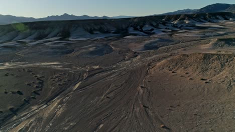 Slow,-aerial-view-moving-toward-dry,-barren-mudstone-embankments-in-a-desert
