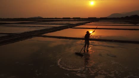 Worker-silhouetted-against-the-golden-evening-sun-raking-the-salt-fields