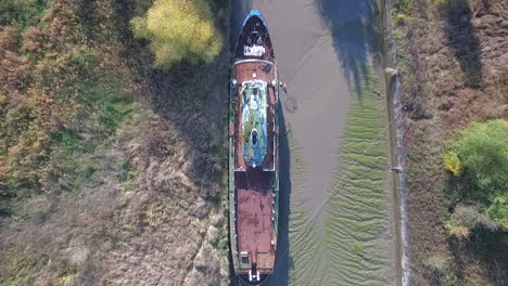 Top-aerial-view-of-a-beautiful-abandoned-ship-in-a-dock-alongside-a-river
