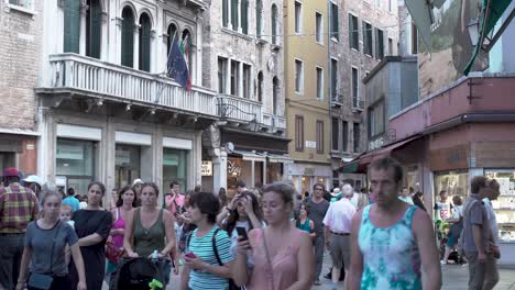 Tourists-fill-a-crowded-European-street-in-Venice,-Italy