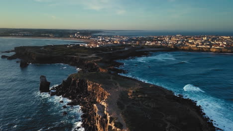 Smooth-aerial-view-of-Papôa's-cliff-on-a-sunny-golden-morning-at-Peniche,-Portugal