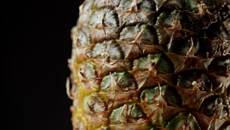 Detailed-macro-shot-of-rotating-pineapple-fruit-isolated-on-black-background
