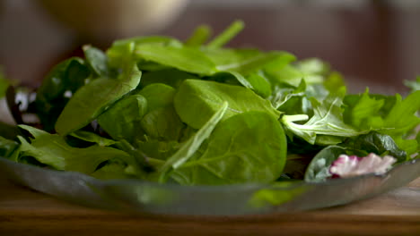 Slow-motion-footage-of-fresh,-green-salad-leaves-falling-on-to-a-plate