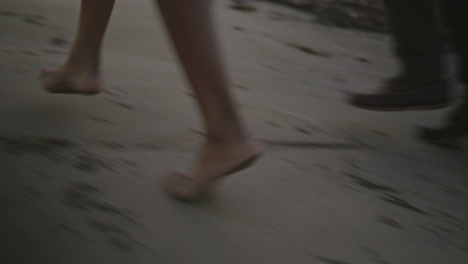 Close-up-of-a-couple's-feet-walking-the-beach