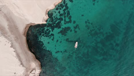 Barco-Moviéndose-Junto-A-Un-Acantilado-En-Una-Pequeña-Bahía-De-La-Patagonia-Desde-Un-Drone-Top-Shot-Sesenta-Fps