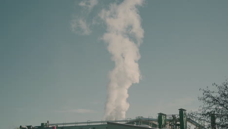 Industrial-factory-with-steam-going-up-in-the-atmosphere,-contributing-to-pollution
