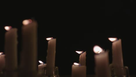 Eine-Extreme-Nahaufnahme-Von-Weißen-Kerzen,-Die-Vor-Schwarzem-Hintergrund-In-Zeitlupe-Angezündet-Werden
