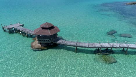 Aerial-of-gazebo-on-a-dock-out-in-the-ocean-on-the-rocks