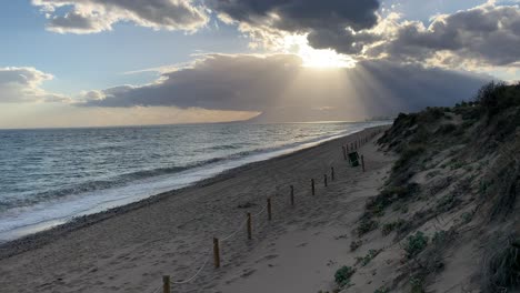 Sonnenstrahlen,-Die-Bei-Einem-Sonnenuntergang-Am-Strand-Durch-Die-Wolken-Stechen