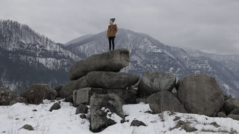 Ein-Mädchen-Steht-Auf-Felsbrocken-Mit-Schneebedeckten-Bergen-Um-Sich-Herum