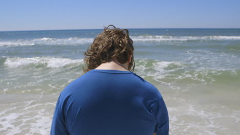 a-teen-boy-gazes-out-at-the-ocean-and-then-walks-away